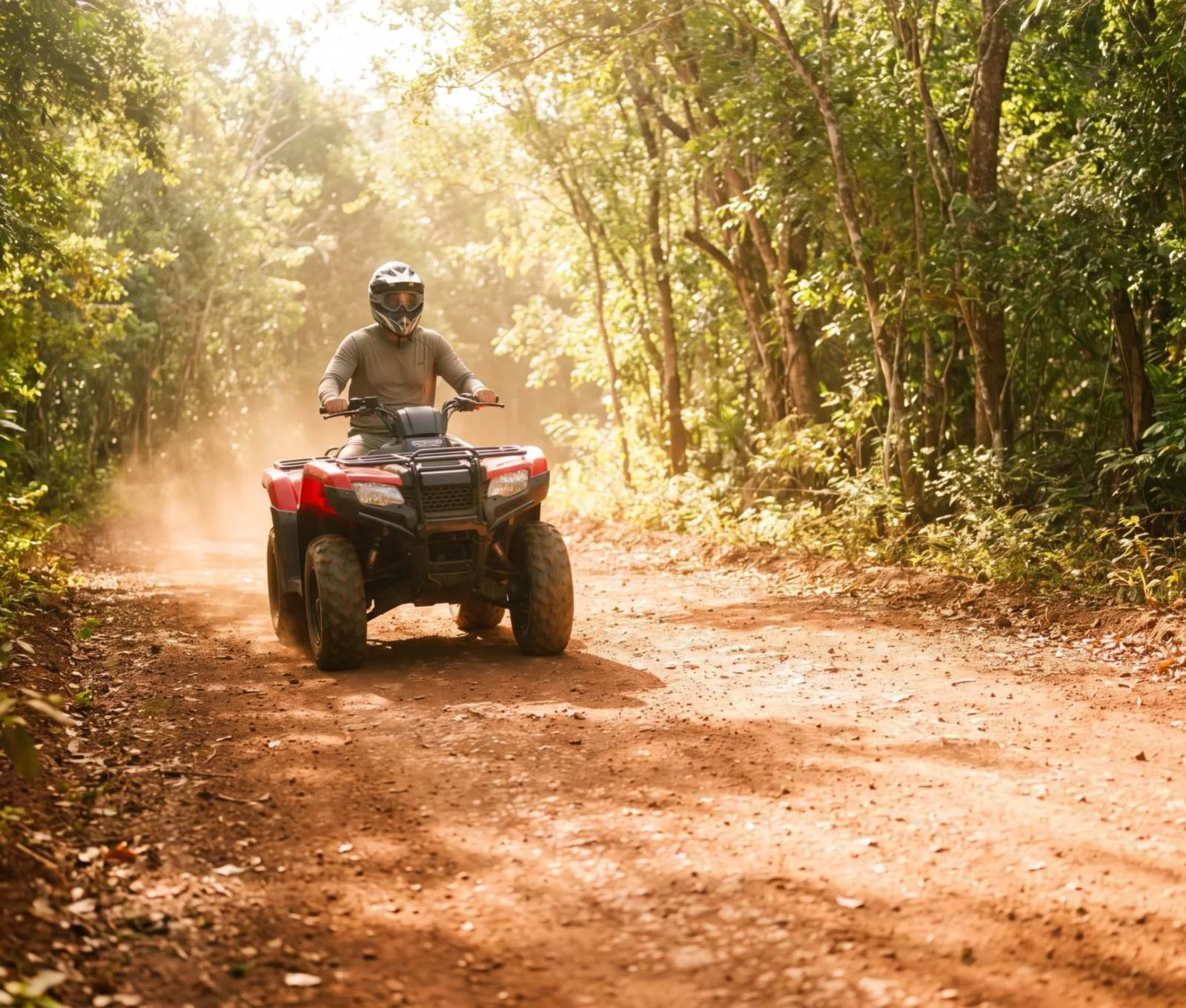 An ATV on a red dirt trail through green forest
