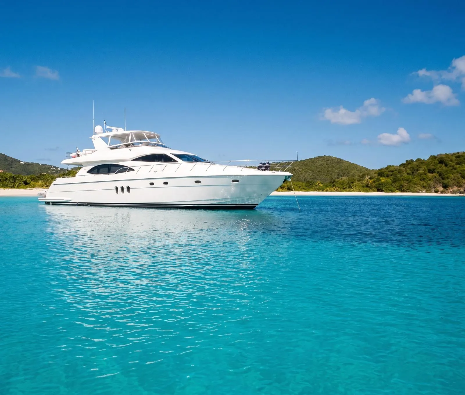 A sleek motor yacht anchored alone in a turquoise bay