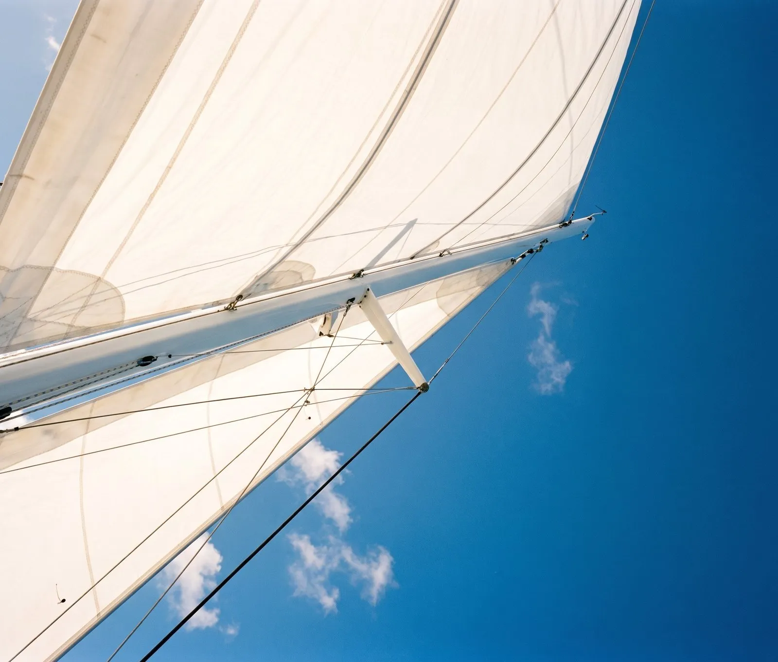 Close-up of a full white sail against blue sky